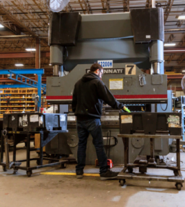 A BTD Manufacturing employee uses a Cincinnnati press brake to bend metal parts.